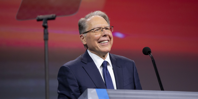 NRA CEO Wayne LaPierre behind lectern smiling