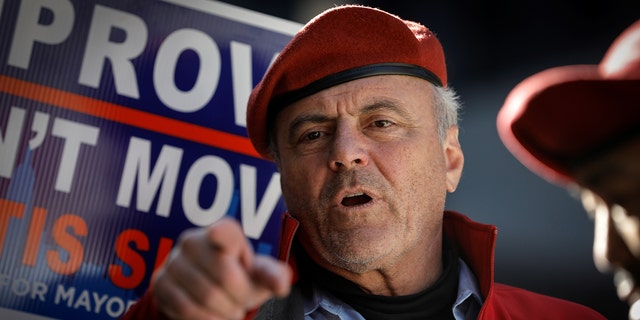 Curtis Sliwa points while wearing his red Guardian Angels hat and jacket