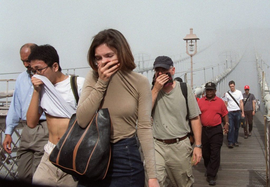 People cover their faces as they move across the Brooklyn Bridge out of the smoke and dust in Manhattan Tuesday Sept. 11, 2001, after a terrorist attack on the twin towers of the World Trade Center. Terrorists hijacked two airliners and crashed them into the World Trade Center in a coordinated series of blows that brought down the twin 110-story towers. (AP Photo/Daniel Shanken)