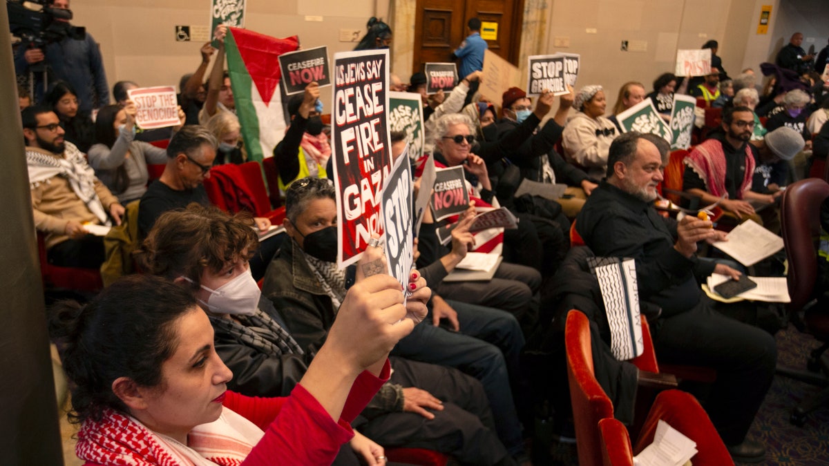 Audience members hold pro-Palestinian signs