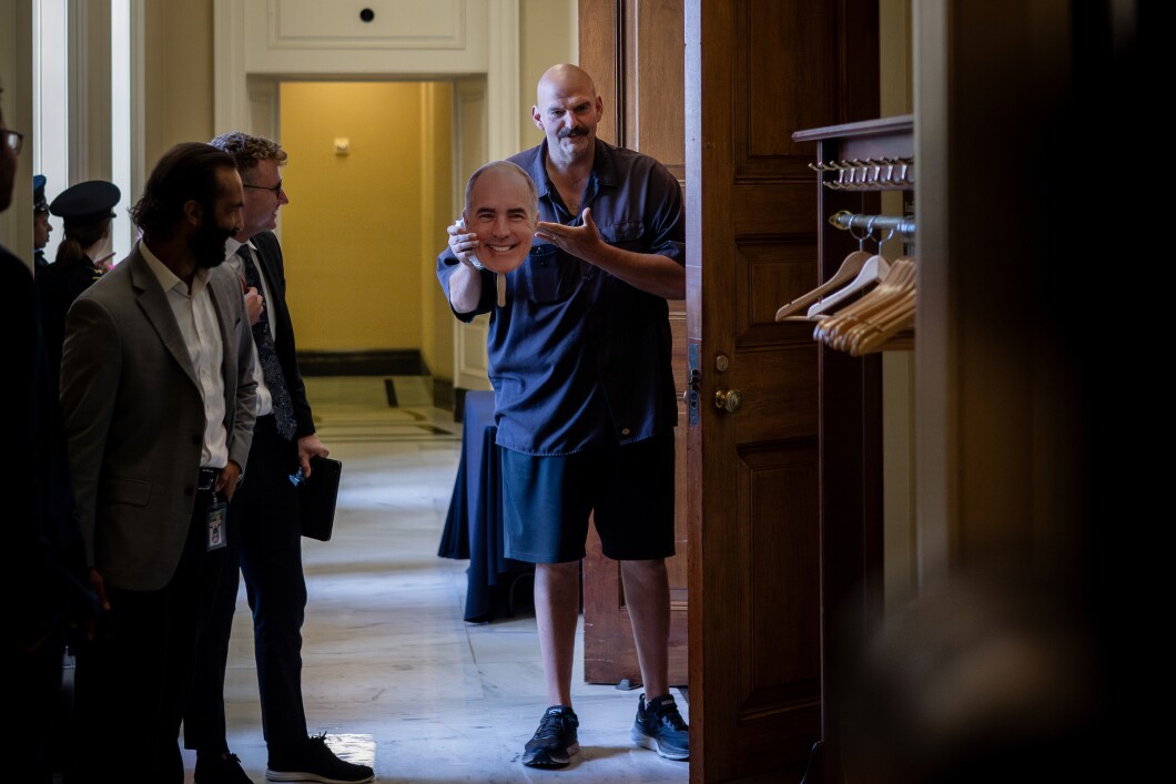 Sen. John Fetterman (D-PA) holds up a face mask of Sen. Bob Casey (D-PA) on Sept. 20, 2023, before arriving at a Democratic luncheon on Capitol Hill. 