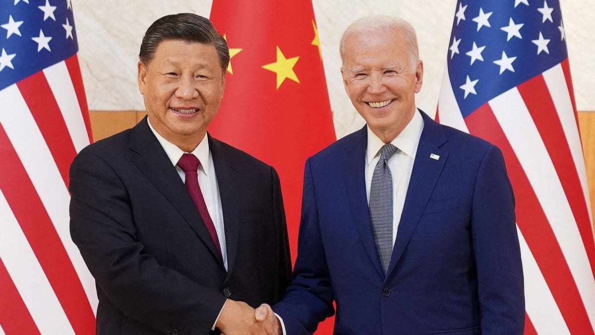 Biden and Xi shake hands in front of the Chinese and US flags