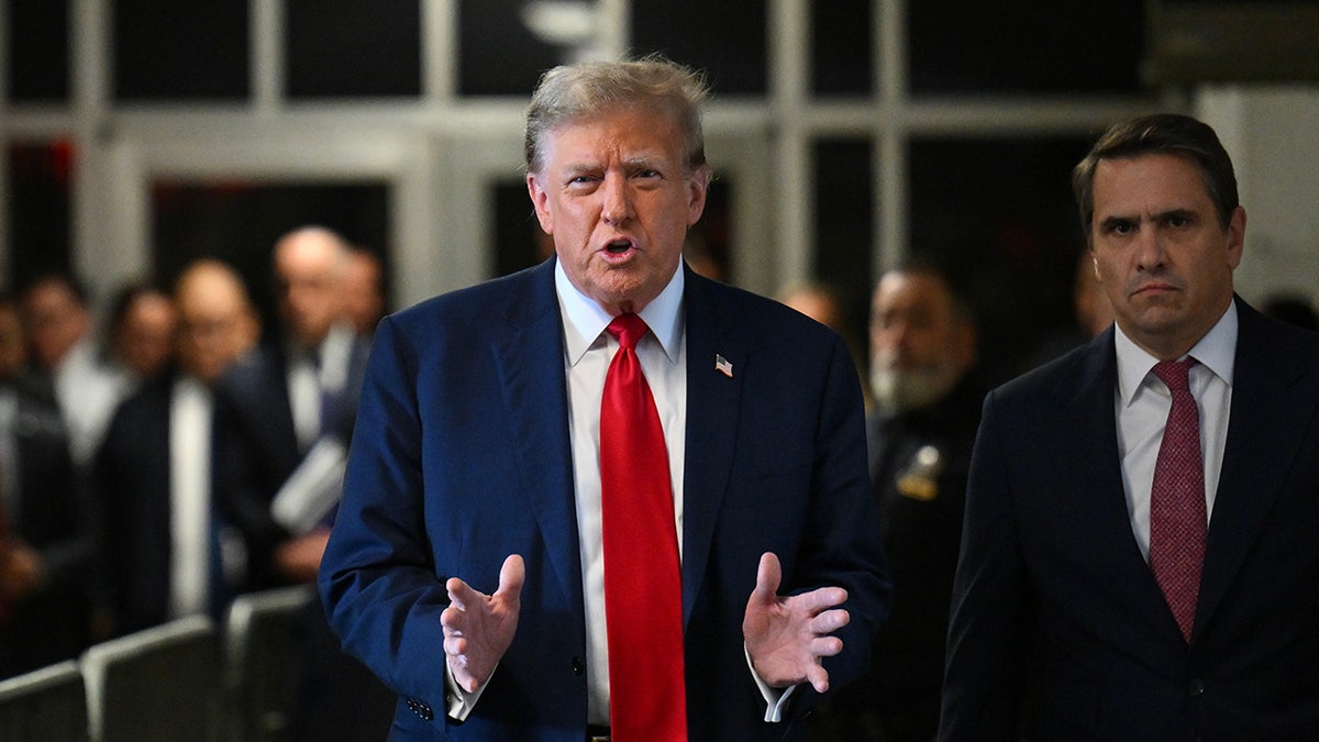 former President Trump in red tie, dark coat speaking to press