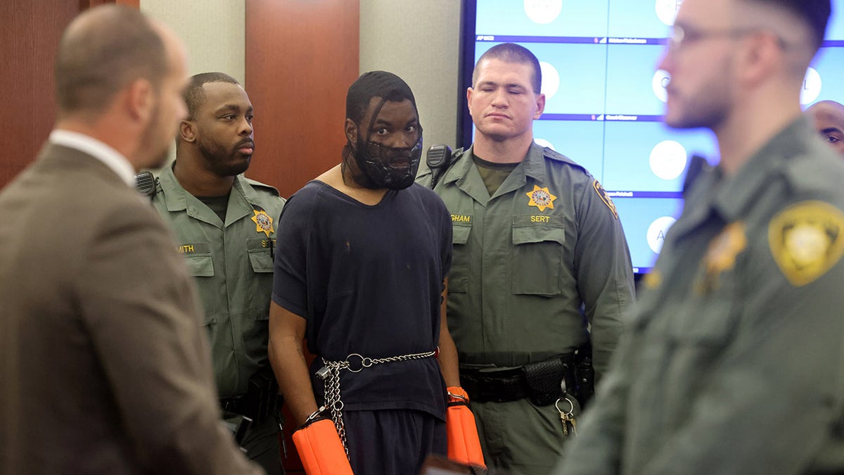 Redden in court with hands bound and mask over face