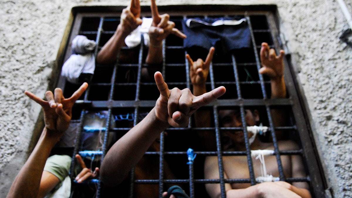 gang members sticking arms thru prison door