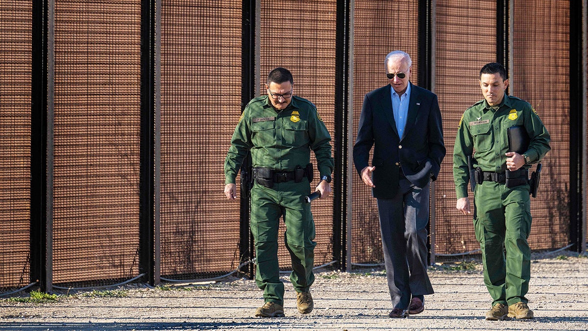 President Biden walking with border officers by wall