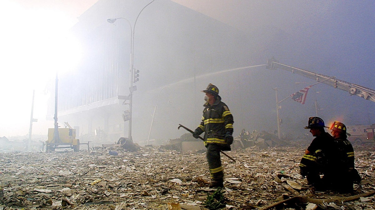 A firefighter walks through rubble of the twin towers of the World Trade Center as a US flag hangs from a traffic light post 11 September, 2001, in New York. Two planes controlled by hijackers crashed into the buildings, destroying both.