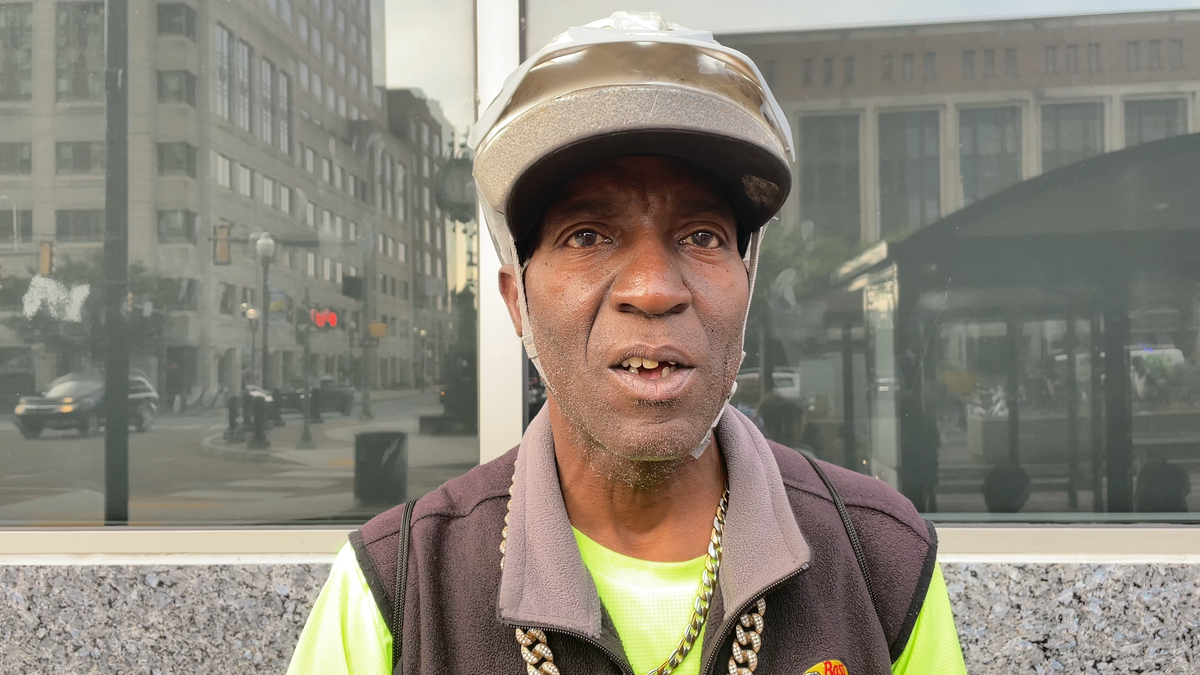 man in hat with building behind him