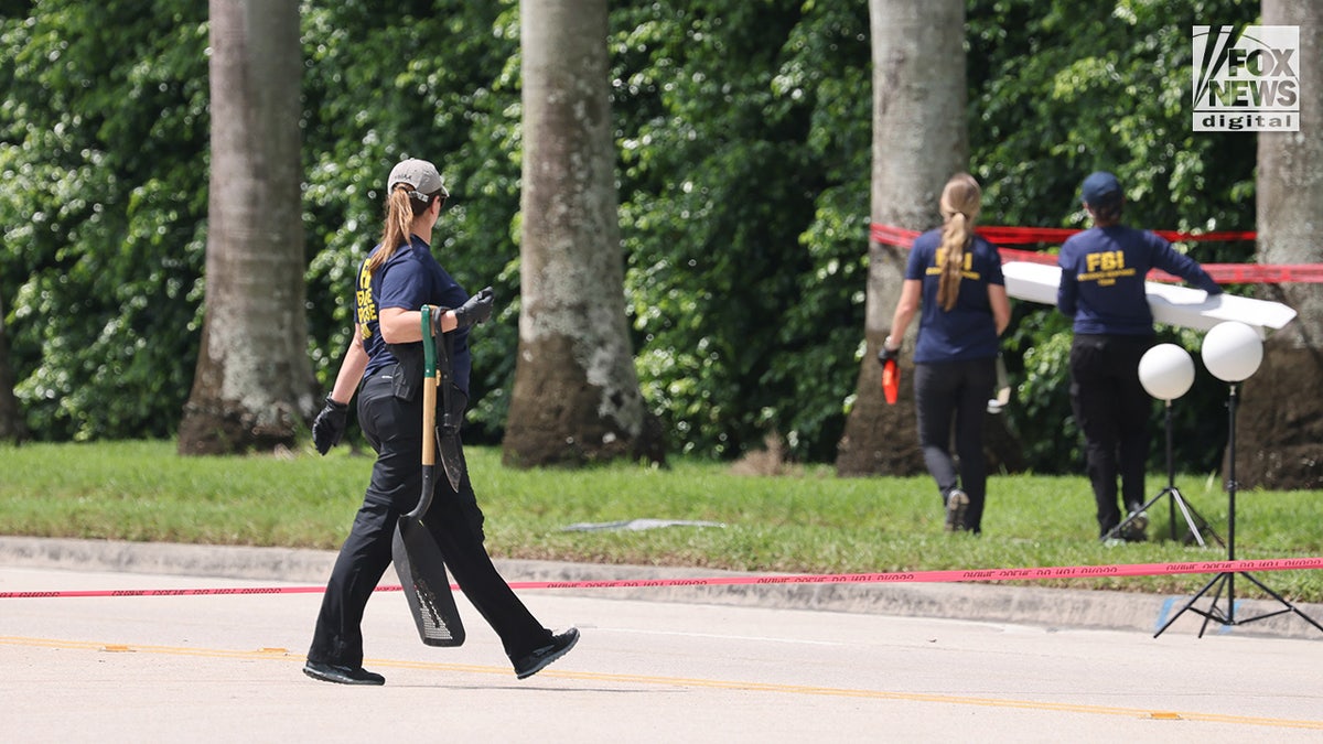 FBI investigators carry a box of evidence from the perimeter of Trump International Golf Club in West Palm Beach