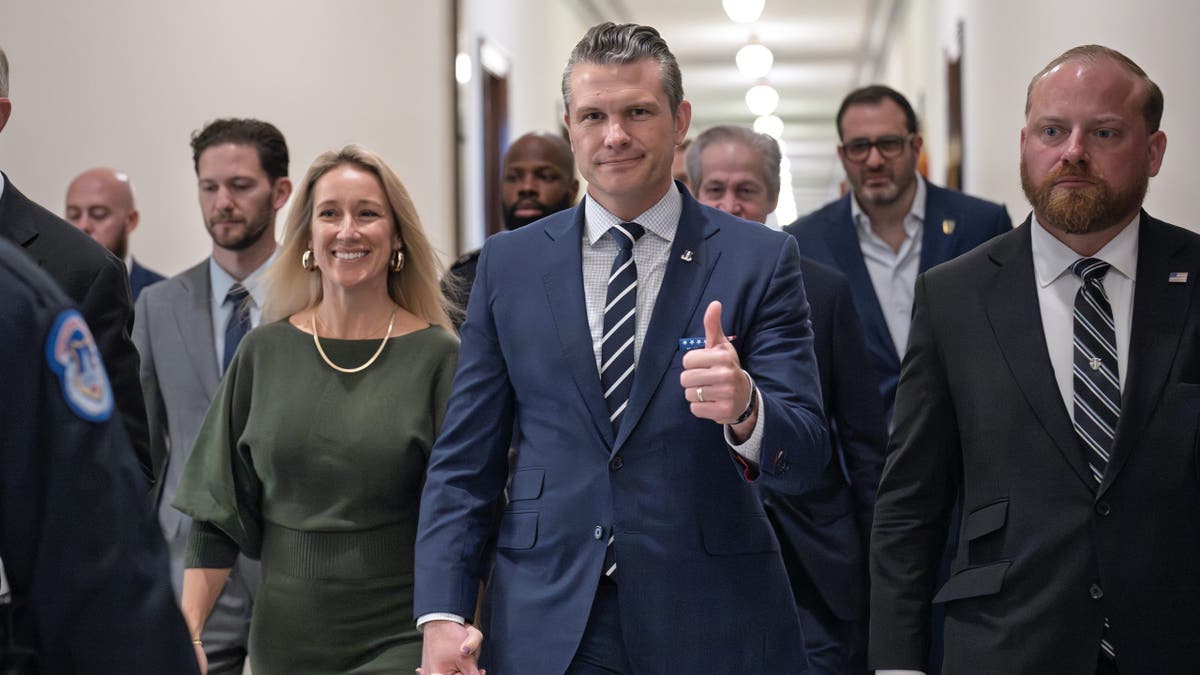 Pete Hegseth, President-elect Trump's nominee for defense secretary, walks with his wife, Jennifer Rauchet, left, to meet with Sen. Joni Ernst, R-Iowa, of the Armed Services Committee at the Capitol on Dec. 9, 2024.