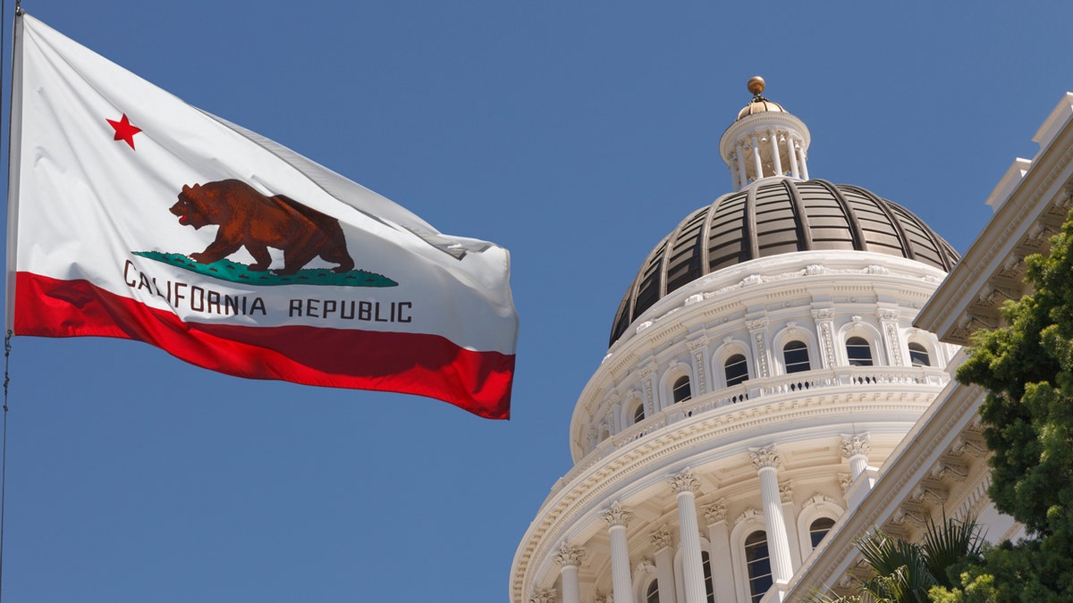 California flag on pole, left with California capitol dome at right