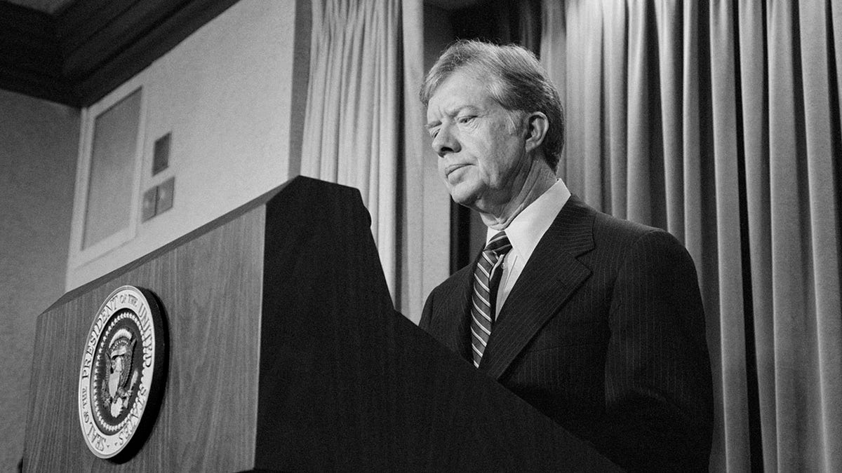 A photo of Jimmy Carter as president in black and white standing at the presidential podium.