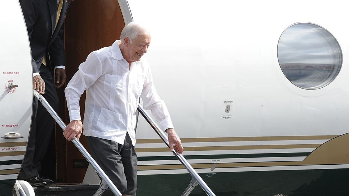 Jimmy Carter, wearing a white button-up shirt, exits a plane upon landing at Havana's international airport 