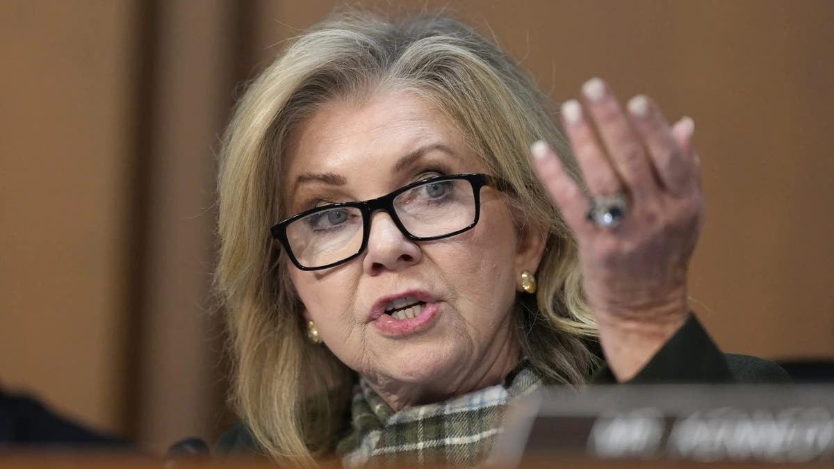 Sen Blackburn lifts her hand while asking a question during a Senate hearing for FBI director nominee Kash Patel