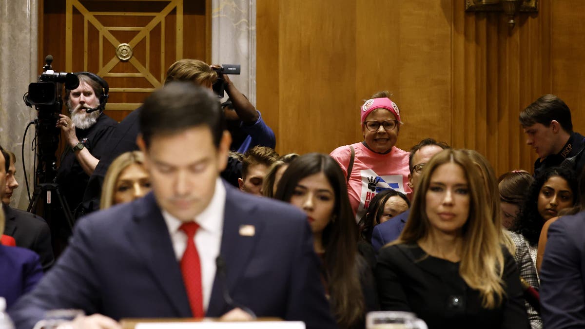 Rubio protester in pink in background, Rubio blurry in foreground