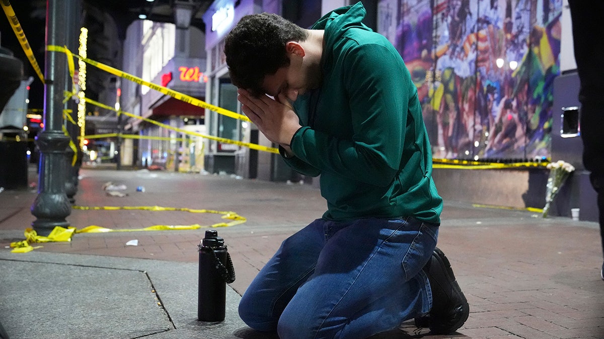 man praying on New Orleans street in front of police tape