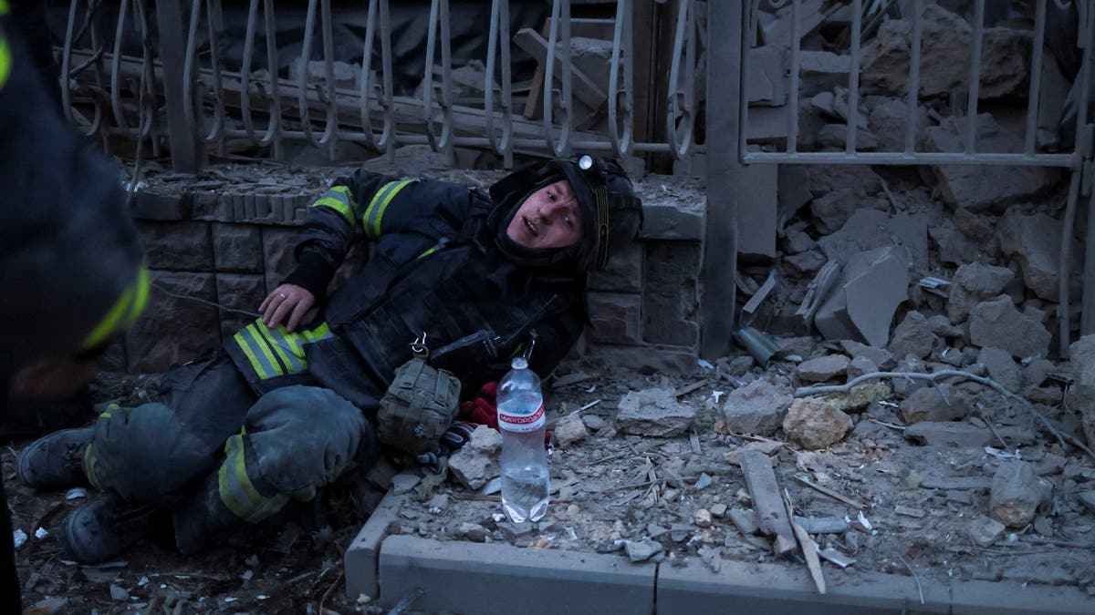 A rescuer rests after works at a site of apartment buildings hit by a Russian air strike, amid Russia's attack on Ukraine, in Kherson, Ukraine