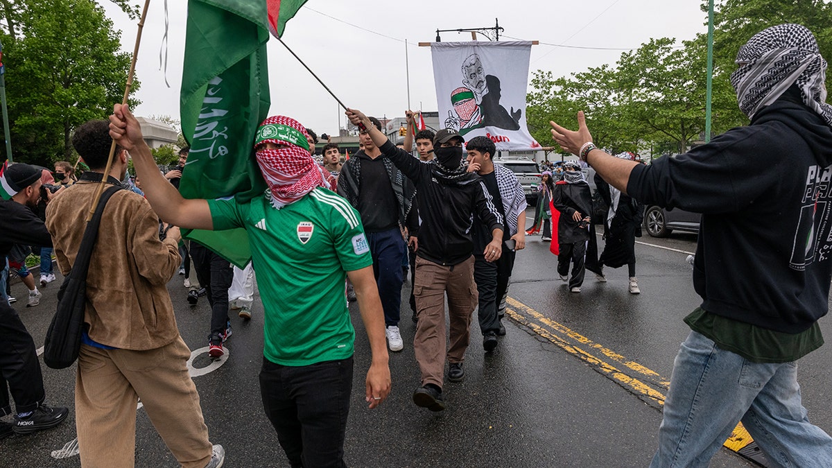 protester holding Hamas flag, wearing Hamas headband