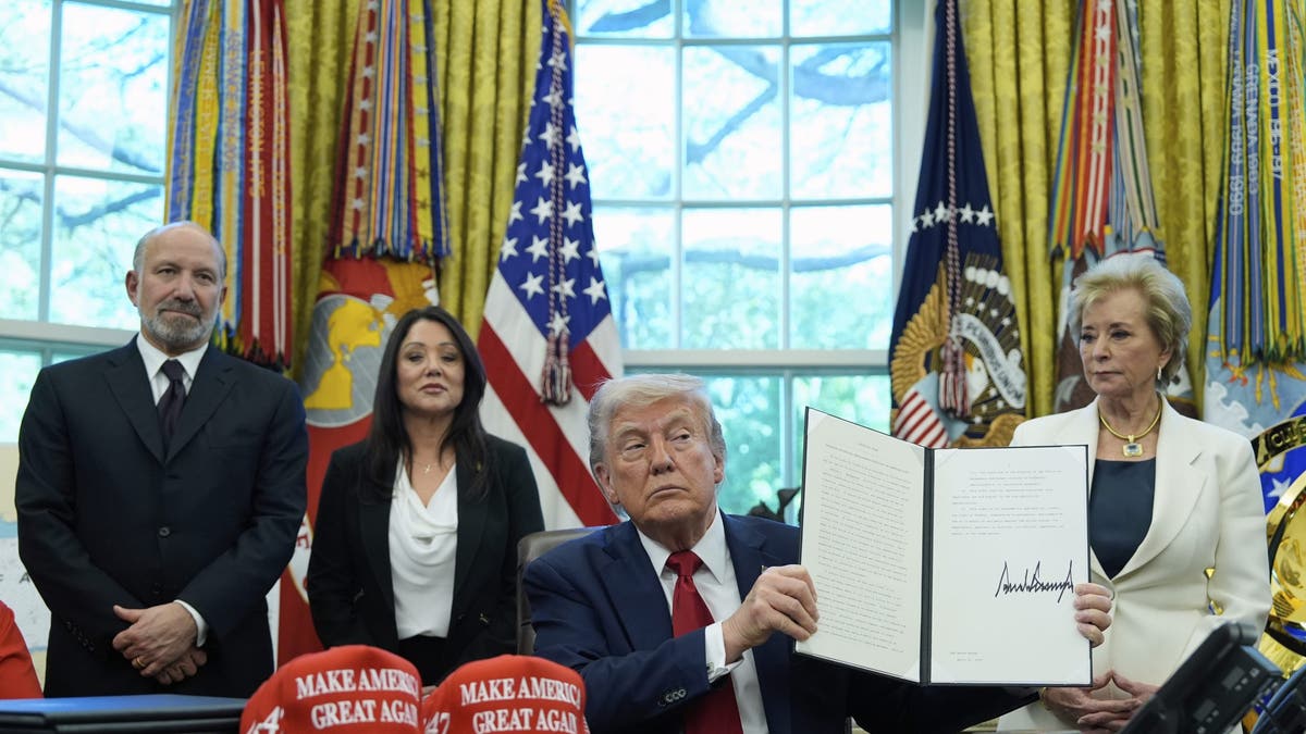 President Donald Trump holds an executive order relating to education in the Oval Office of the White House, Wednesday, April 23, 2025, in Washington, as Commerce Secretary Howard Lutnick, Labor Secretary Lori Chavez-DeRemer and Education Secretary Linda McMahon watch. (AP Photo/Alex Brandon)
