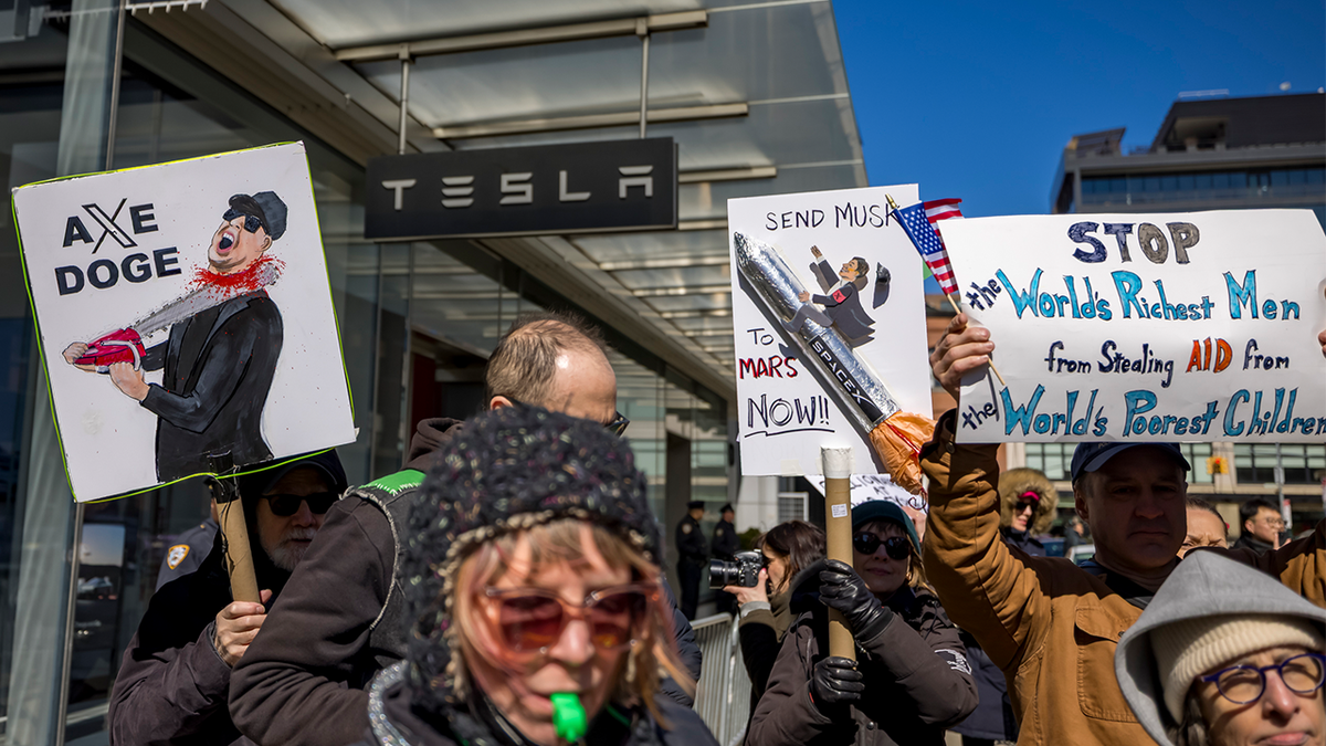 Hundreds protest outside a Tesla showroom to show their disapproval of Elon Musk and the Department of Government Efficiency.