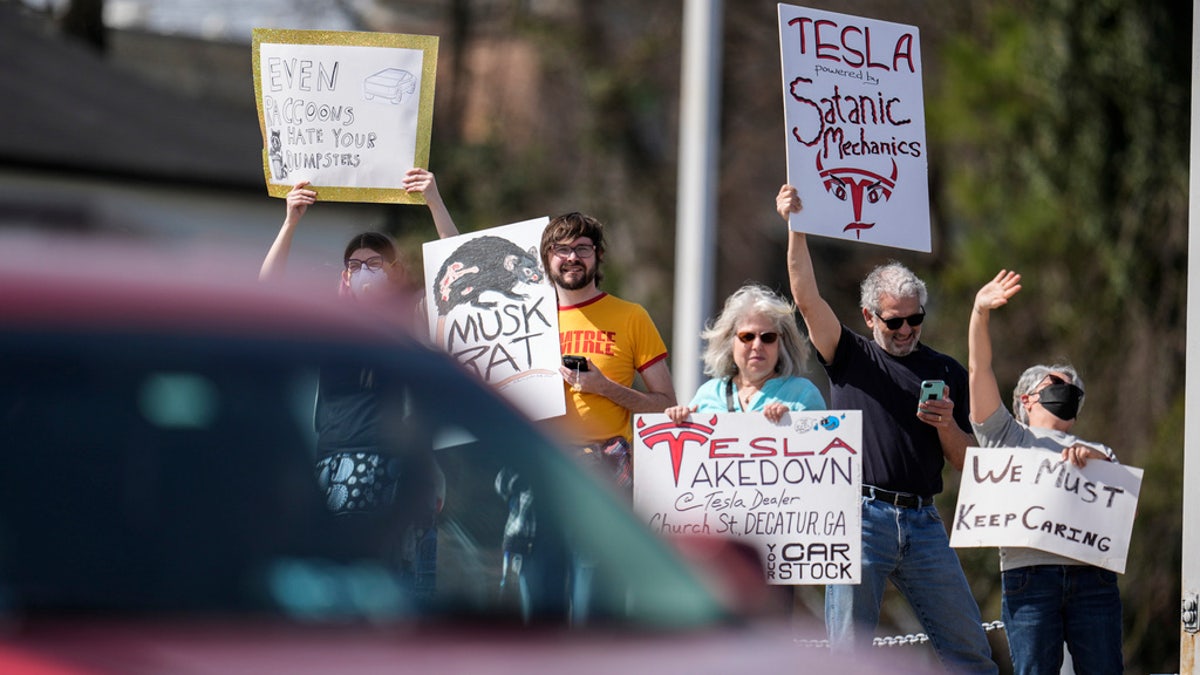 People protest automaker billionaire CEO Elon Musk near a Tesla vehicle dealership, March 8, 2025, in Decatur, Ga.