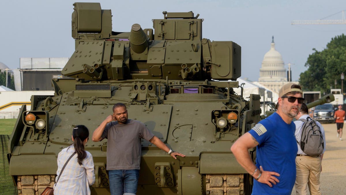 People pass by and take photos with a tank, parked on the National Mall, during preparations for an upcoming military parade commemorating the Army's 250th anniversary and coinciding with President Donald Trump's 79th birthday, Thursday, Jun. 12, 2025, in Washington.