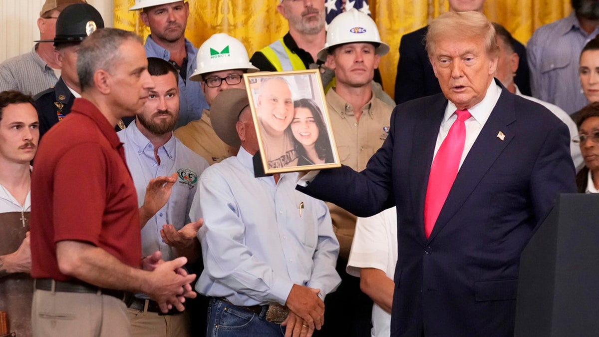 President Donald Trump holds a photo of Katie Abraham.