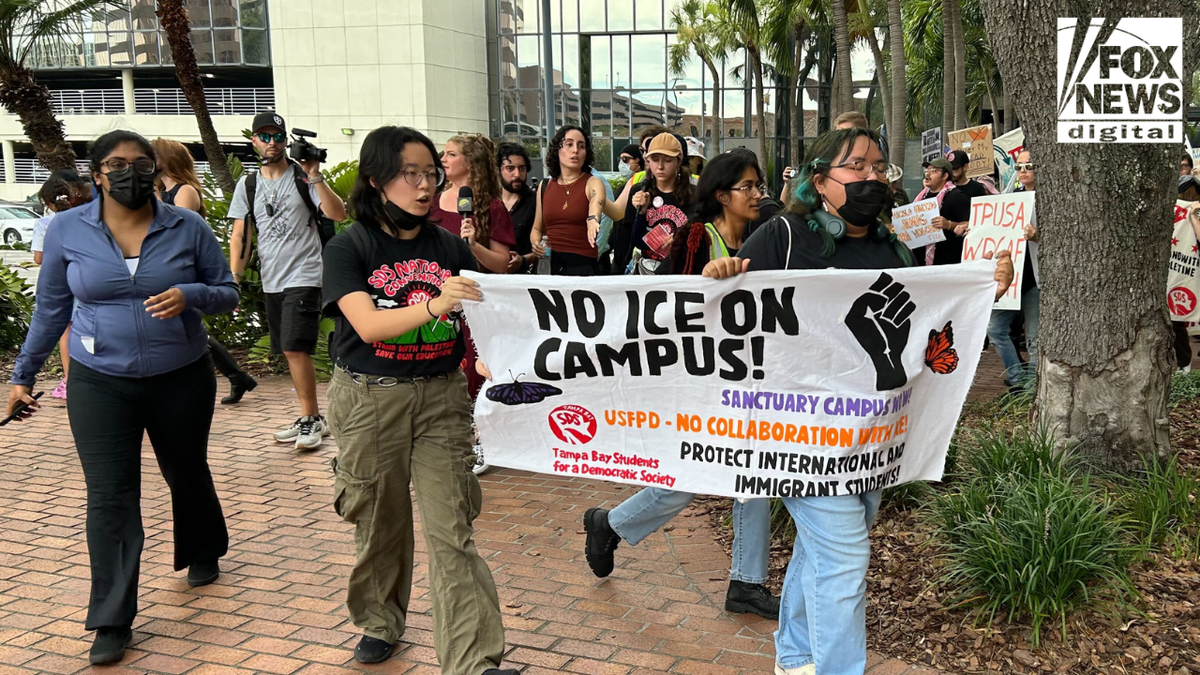 Protesters hold a "No ICE on campus!" sign outside Turning Point USA's Student Action Summit.
