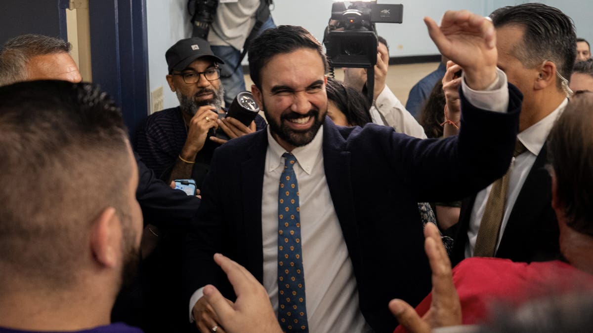 Mamdani smiling in midst of media gaggle