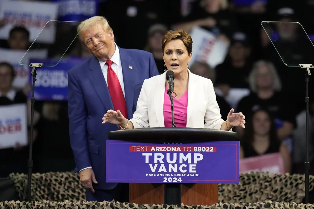 Republican presidential nominee former President Donald Trump listens as Arizona Senate candidate Kari Lake speaks at a campaign rally at the Findlay Toyota Arena Sunday, Oct. 13, 2024, in Prescott Valley, Ariz. 
