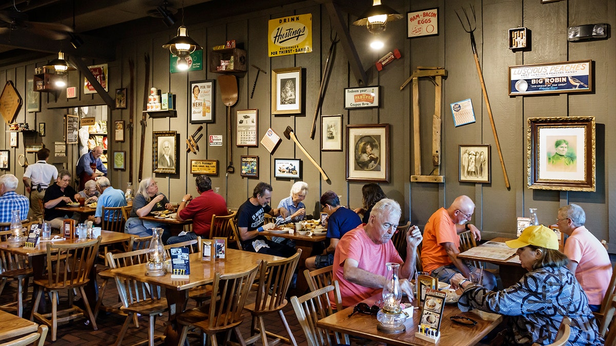 Cracker Barrel Old Country Store customers eat inside a restaurant with antiquities on the wall.
