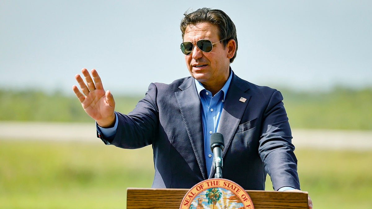 Florida Gov. Ron DeSantis wearing sunglasses and holding his hand in out in front of himself