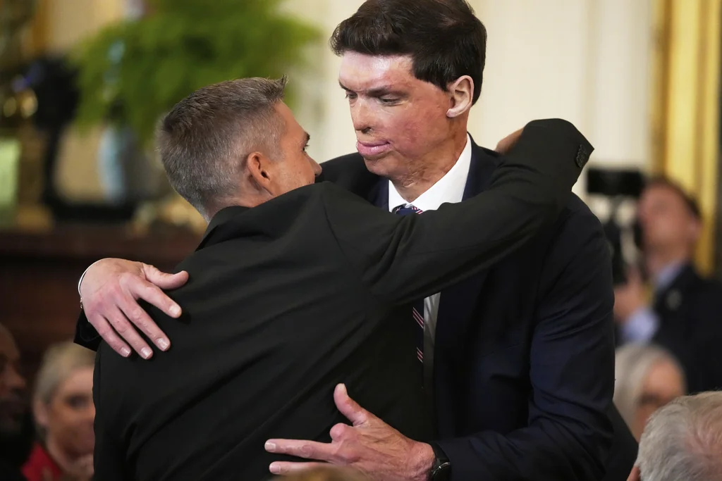 Kevin Jensen, left, hugs Samuel Brown, Under Secretary for Memorial Affairs, as President Donald Trump holds an event to mark National Purple Heart Day in the East Room of the White House, Thursday, Aug. 7, 2025, in Washington.