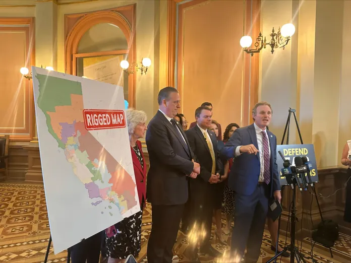 Assembly Republican leader James Gallagher speaks in front a poster showing California's congressional districts.
