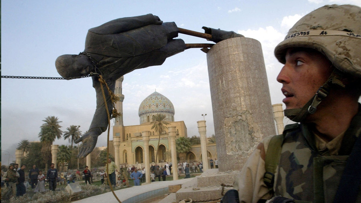 A U.S. soldier watches as a statue of Iraq's President Saddam Hussein falls in central Baghdad, April 9, 2003.