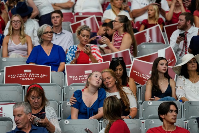 People sit inside before the start of a memorial for conservative activist Charlie Kirk, Sunday, Sept. 21, 2025, at State Farm Stadium in Glendale, Ariz. (AP Photo/John Locher)