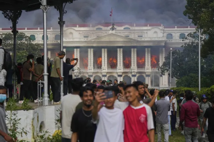 Protesters take selfies and celebrate at the Singha Durbar, the seat of Nepal's government's various ministries and offices, after it was set on fire during a protest against social media ban and corruption in Kathmandu, Nepal, Tuesday, Sept. 9, 2025.
