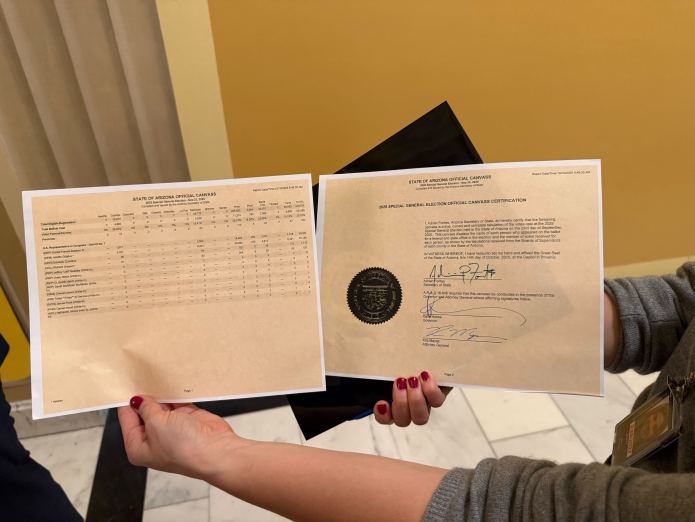 A staffer for Rep. Greg Stanton (D-AZ) displays the certification of Adelita Grijalva's special election win to Arizona's 7th Congressional District. (Lauren Green/Washington Examiner)