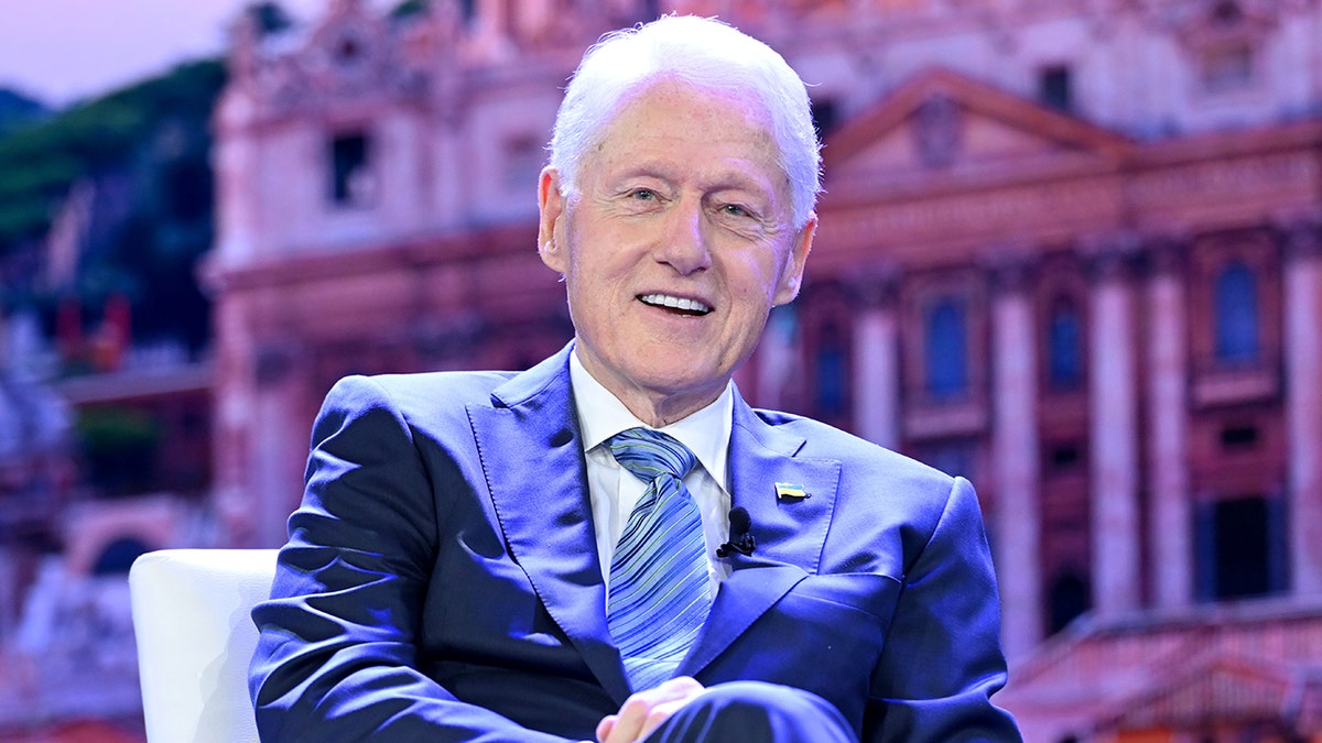 Former President Bill Clinton smiling while sitting in a chair.
