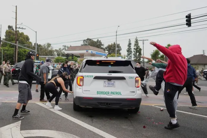 Protesters kick the side of a Border Patrol vehicle.