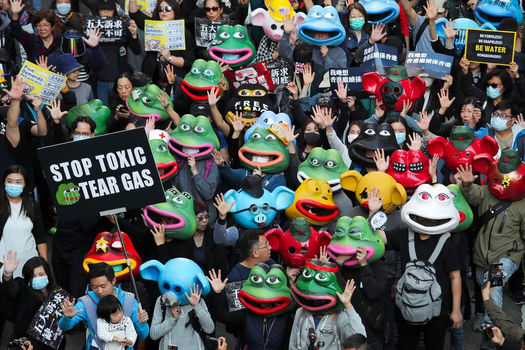 Pro-democracy protesters wear masks, including those for Pepe the Frog, during a march.