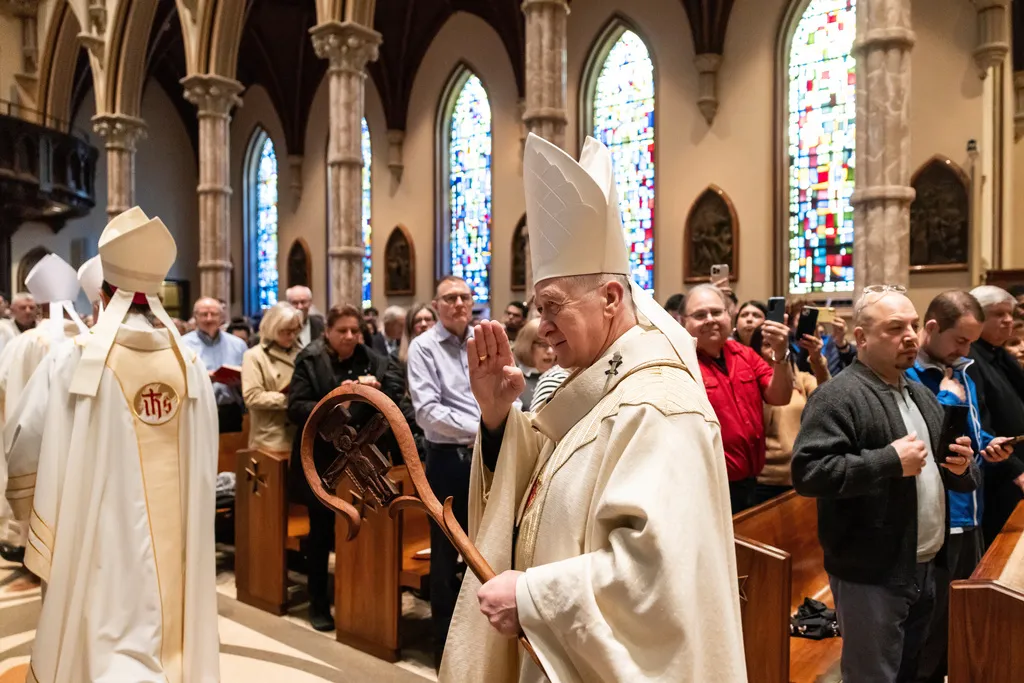 Archdiocese of Chicago Cardinal Blase Cupich gives blessings as he exits the church with other priests.