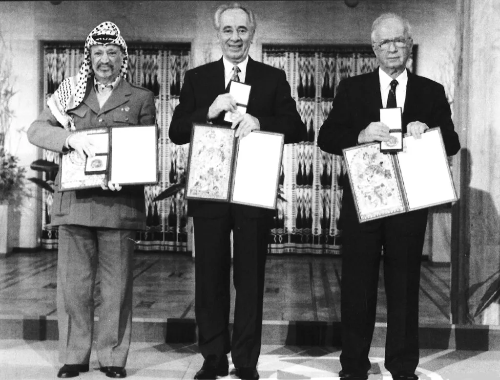 PLO leader Yasser Arafat, Israeli Prime Minister Yitzhak Rabin, and Israeli Foreign Minister Shimon Peres pose with their Nobel Peace Prize medals and diplomas.