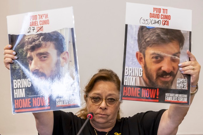 Silvia Cunio mother of the hostages Ariel Cunio, left, and David Cunio, right, holds pictures of her sons, during a press conference organized by the Geneva Association of United Nations Correspondents (ACANU), at the European headquarters of the United Nations in Geneva, Switzerland, Tuesday, Aug. 12, 2025. (Salvatore Di Nolfi/Keystone via AP)