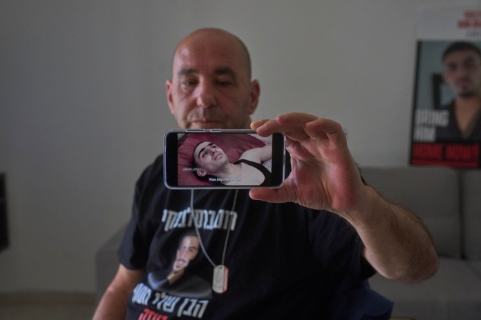 Ofir Braslavski shows a video from militant group Palestinian Islamic Jihad, published last week of his son Rom gaunt and emaciated in captivity in Gaza, in Almon, an Israeli settlement in the West Bank, Monday, Aug. 04, 2025. (AP Photo/Ohad Zwigenberg)