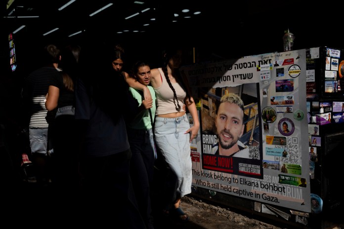 People walk next to the market stand belonging to Elkana Bohbot, who was kidnapped from the Nova festival and has not been released from Gaza in the Carmel Market in Tel Aviv, Israel, Sept. 27, 2024.(AP Photo/Ohad Zwigenberg)