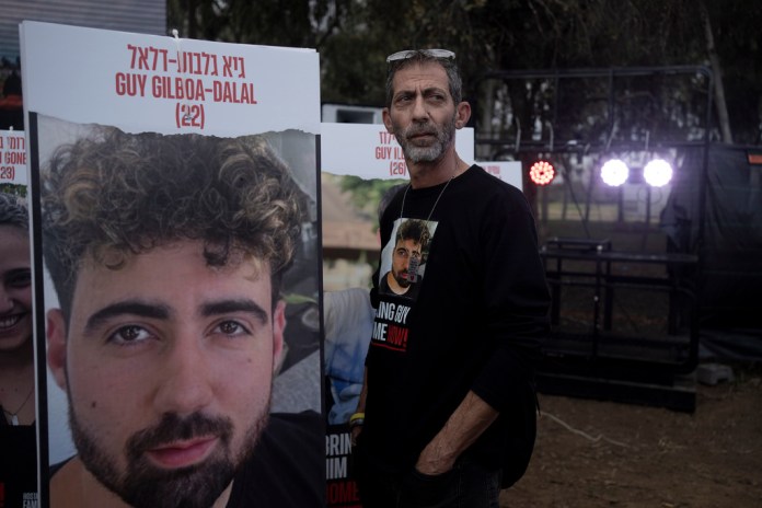 Ilan Dalal, father of Guy Gilboa-Dalal, who was kidnapped on Oct. 7 in a cross-border attack by Hamas at the Nova music festival, stands next to a photo of his son during a press conference at the site in Re'im, southern Israel, Friday, Jan. 5, 2024. (AP Photo/Maya Alleruzzo)