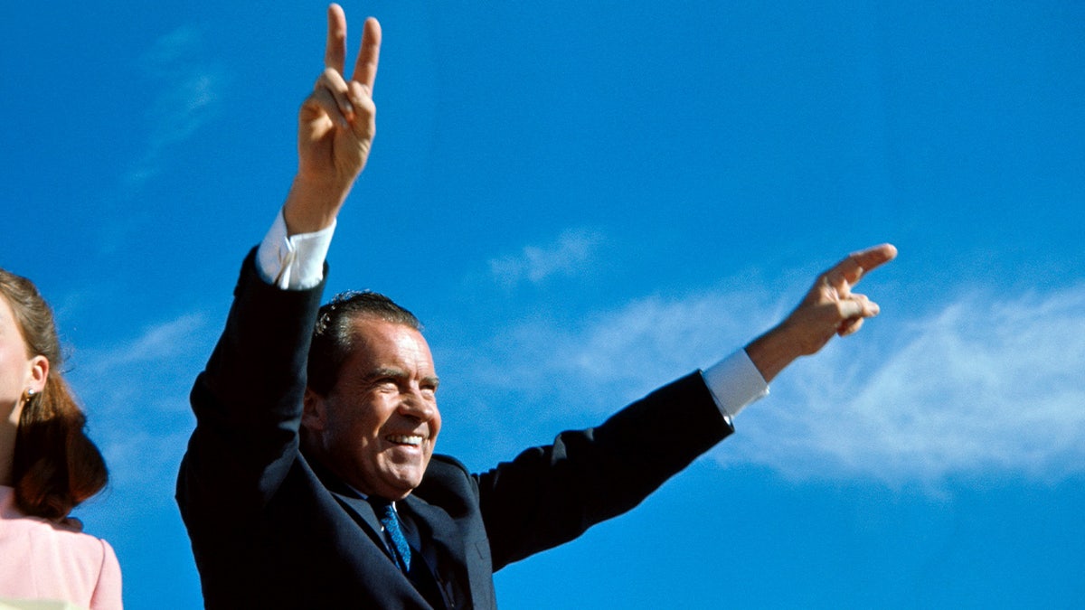 Richard Nixon greeting people with his arms up 