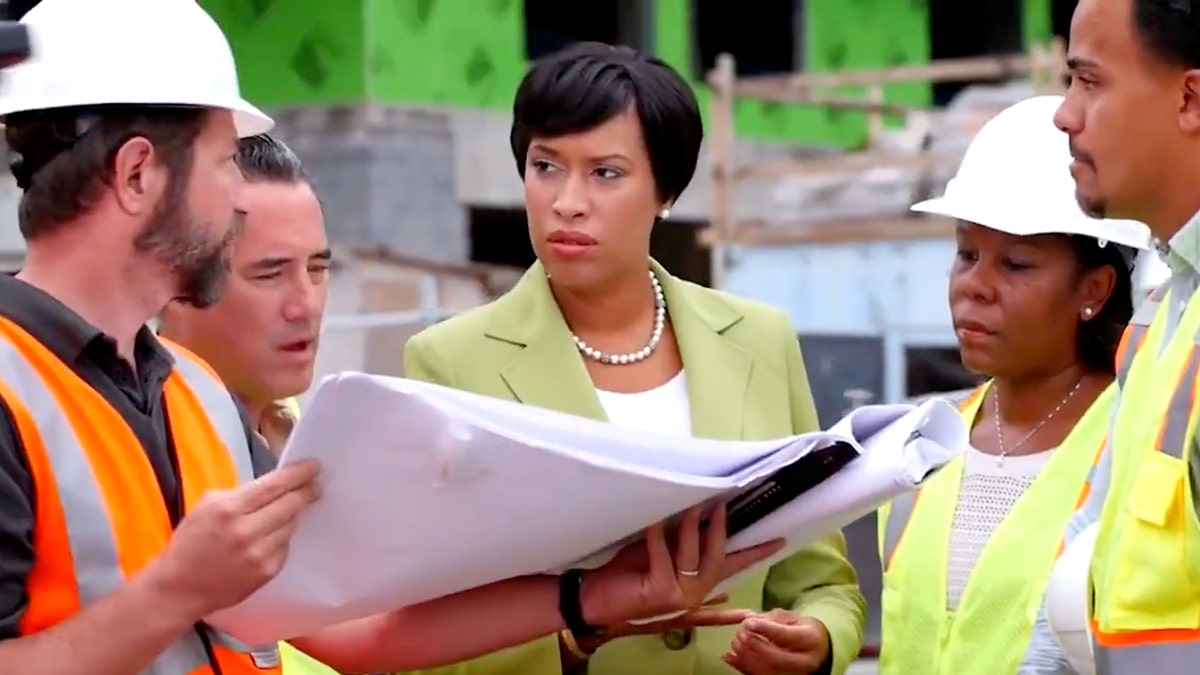 Muriel Bowser poses with construction workers in an announcement video.