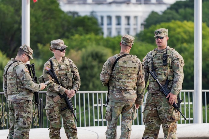 With the White House in the distance, National Guard troops patrol the National Mall.